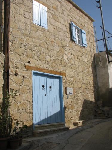 a stone building with a blue door on it at Dolphin Guest House and Studios in Tochni