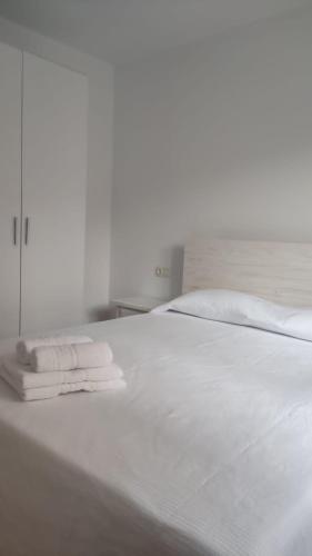 Una cama blanca con dos toallas plegables. en Villa Xunqueira 2, en Cee