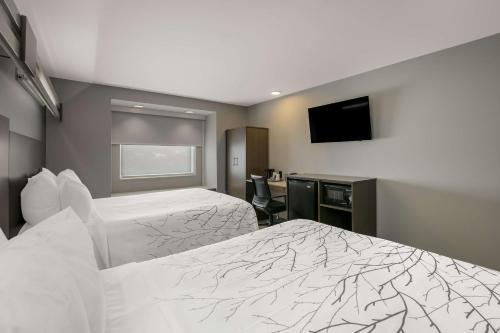 a hotel room with two beds and a flat screen tv at SureStay Plus Hotel by Best Western Sevierville in Sevierville
