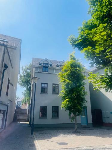 a white building with a tree in front of it at Ballina Town Centre Duplex Apartment in Ballina