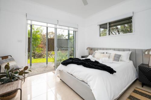 Un dormitorio blanco con una cama y una ventana grande. en URALLA STUDIO - South Coast - Private Guest Suite, en Bomaderry