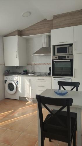 a kitchen with white cabinets and a table and a microwave at Villa Xunqueira 3 in Cee