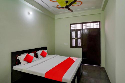 1 dormitorio con 1 cama grande con almohadas rojas y blancas en OYO Flagship J M K Love Residency en Noida
