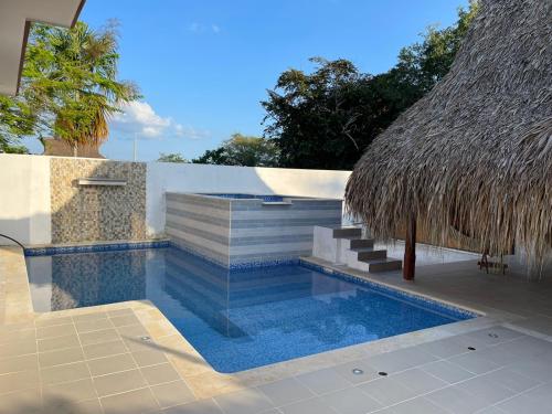 a swimming pool with stairs and a thatch roof at Casa Finca La 58 Melina Real 