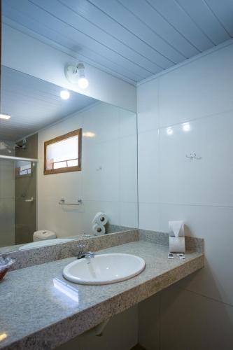 a bathroom with a sink and a mirror at Pousada Aldeia Portuguesa in Coroa Vermelha