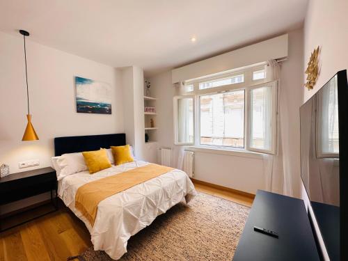 ein Schlafzimmer mit einem Bett mit gelben Kissen und einem TV in der Unterkunft Vaibar Apartaments en el centro de Vigo entorno plaza de Compostela in Vigo