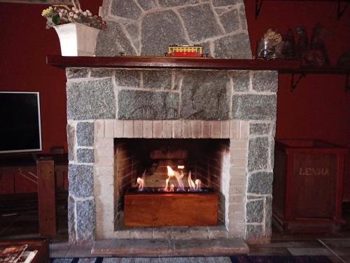 a stone fireplace with a fire in it at Casa do Passarinho in Campos do Jordão