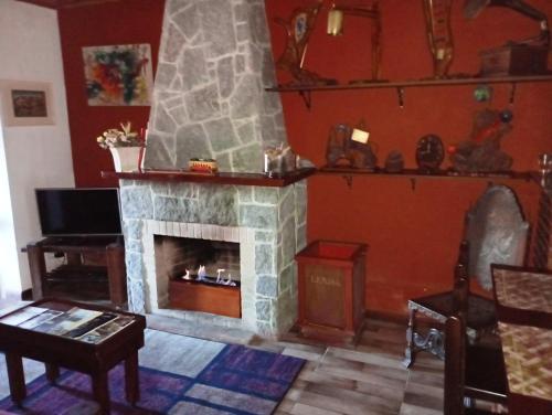 a living room with a stone fireplace and a table at Casa do Passarinho in Campos do Jordão