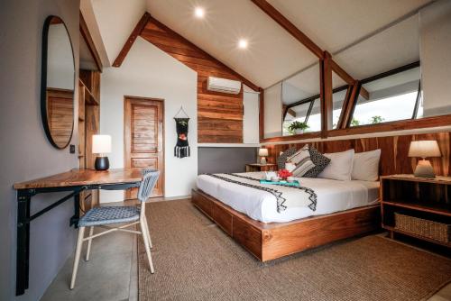 a bedroom with a bed and a desk in a room at Surf Synergy All-Inclusive Surf Retreat in Jacó