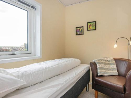 ein Bett und ein Stuhl in einem Zimmer mit einem Fenster in der Unterkunft Holiday home Lemvig XXX in Lemvig