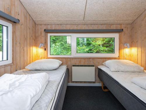 two beds in a small room with two windows at Holiday home Glesborg VI in Glesborg