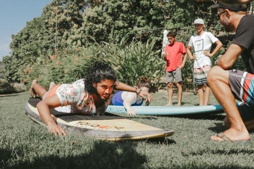 a man laying on a surfboard in the grass at Surf Synergy All-Inclusive Surf and Wellness Retreat in Jacó