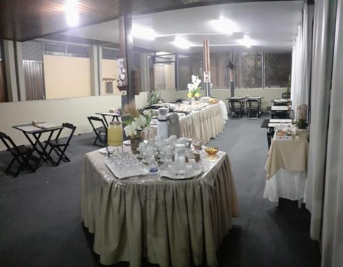 a group of tables in a room with white table cloth at Falcon Hotel in Bauru