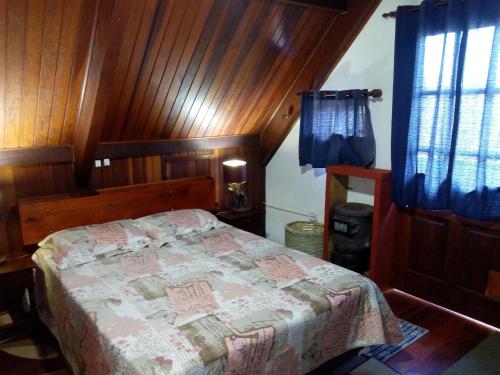 a bedroom with a bed in a room with wooden walls at Casa do Passarinho in Campos do Jordão