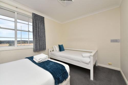 a bedroom with two beds and a window at Beggars Bridge Vineyard Homestead with pool and tennis in Rothbury