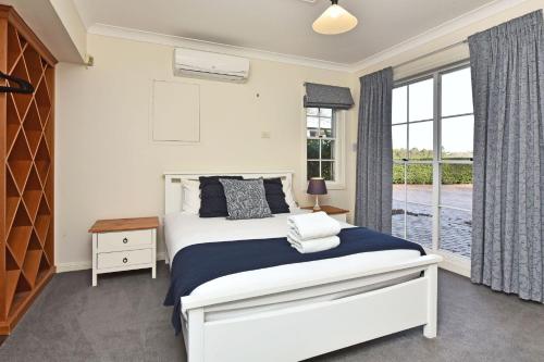 a bedroom with a bed and a large window at Beggars Bridge Vineyard Homestead with pool and tennis in Rothbury
