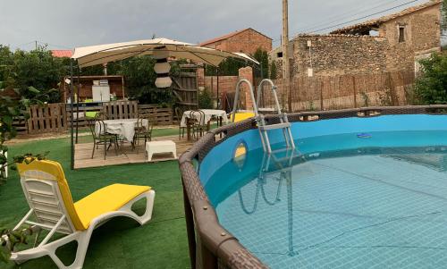 a swimming pool with chairs and a table and an umbrella at CASA NOTARI - Casa Rural Zona Congost de Montrebei in Tolva