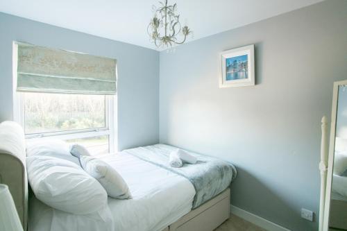 a bedroom with a bed with white sheets and a window at So-Cute Cityside in Belfast