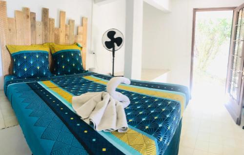 Un dormitorio con una cama azul con una toalla. en Top Hill appartements et dortoir - Martinique, en La Trinité
