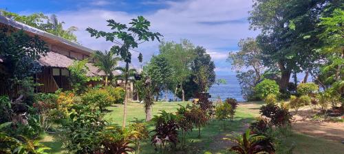 a garden with trees and the ocean in the background at Bohol-Lahoy Dive Resort in Guindulman
