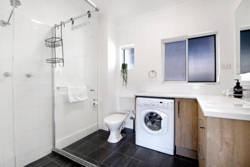 a bathroom with a toilet and a sink and a washing machine at Ocean Spray 7 in Coffs Harbour