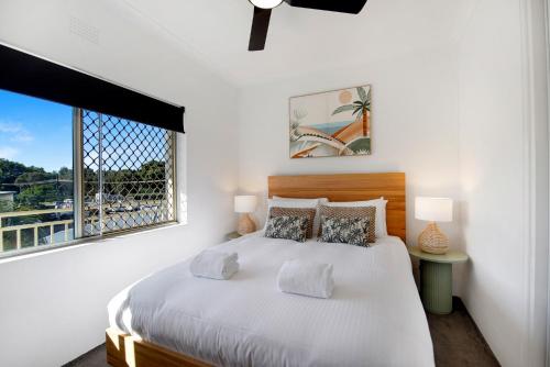 a white bedroom with a large bed and a window at Ocean Spray 7 in Coffs Harbour
