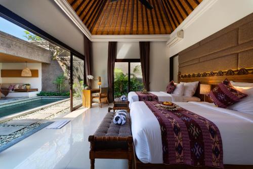 a bedroom with two beds and a swimming pool at Adepa Resort in Canggu