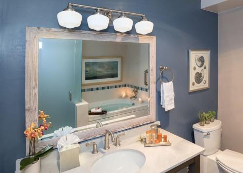ein Badezimmer mit einem Waschbecken und einem großen Spiegel in der Unterkunft Sand Pebbles Inn in Cambria
