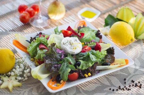 a plate of food with a salad on a table at CASA Di VINA Boutique Hotel in Salvador