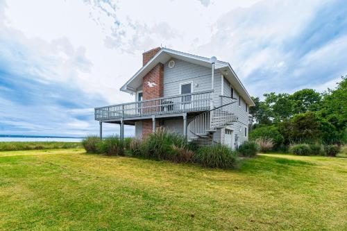 a white house with a balcony and a grass field at Watersedge Retreat in Southold