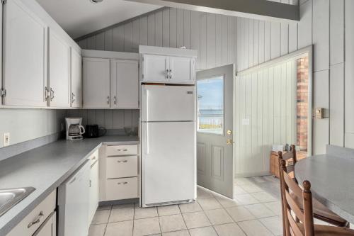 a kitchen with white cabinets and a refrigerator at Watersedge Retreat in Southold