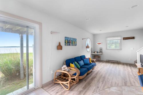 a living room with a blue couch and a sliding glass door at Watersedge Retreat in Southold