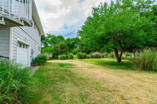 a yard with a tree next to a house at Watersedge Retreat in Southold
