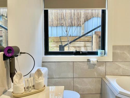 a bathroom with a window and a toilet and a sink at Arthurs Holiday Villa in Arthurs Seat