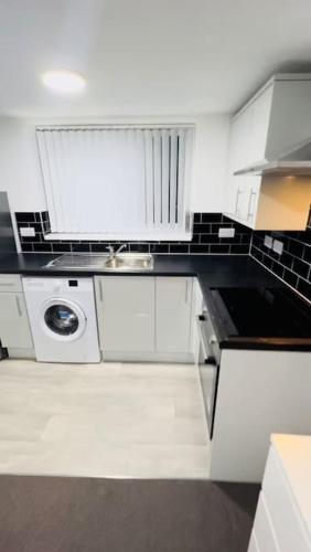 a white kitchen with a sink and a dishwasher at Cosy Apartment Next To City Centre in Sheffield