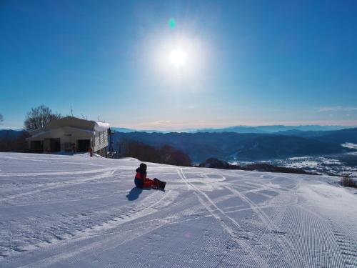 une personne assise dans la neige sur une piste de ski dans l'établissement ホテルにれの樹, à Hakuba