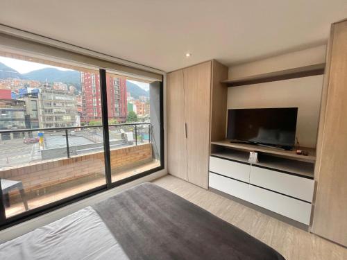 a bedroom with a large window and a television at Hermosa Vista en Chapinero cómodo wifi in Bogotá