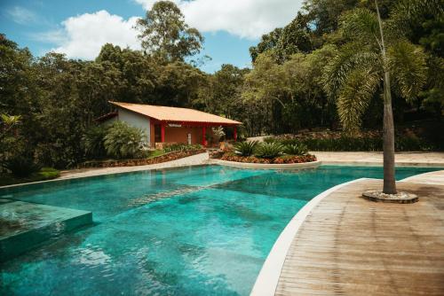 uma piscina com um passadiço de madeira ao lado de uma casa em Cachoeira do Macuco Boutique Hotel em Guapé