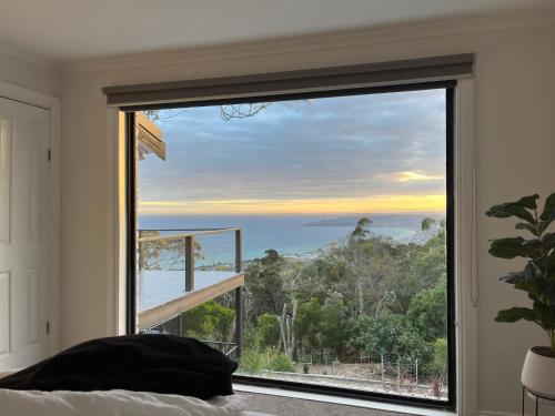 a bedroom with a large window with a view of the ocean at Arthurs Holiday Villa in Arthurs Seat