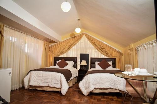 a bedroom with two beds and a table at Bolivian Rooms & Suites (Zona Sur) in La Paz