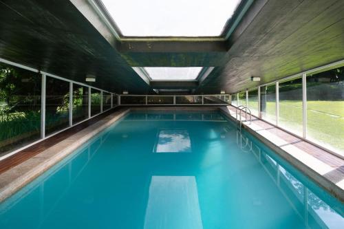 an indoor swimming pool with blue water and windows at Quinta das Gerais in Marco de Canaveses