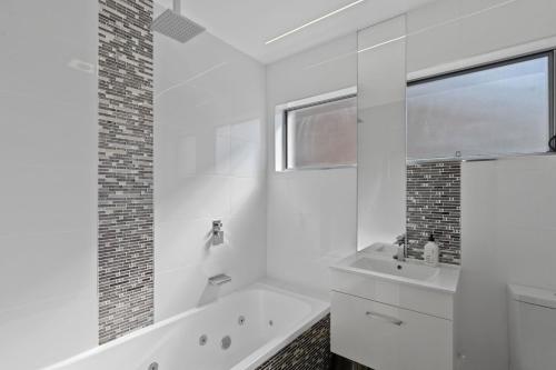 a white bathroom with a tub and a sink at 4 bedroom fabulous home on canal in Mooloolaba