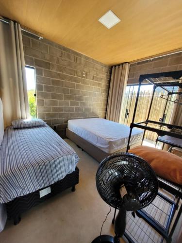 a room with two beds and a fan in it at Villa Maré Guaratiba Beach in Prado