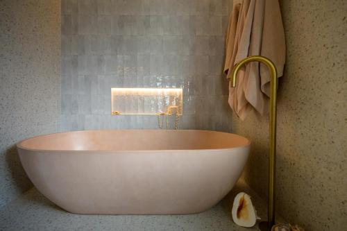 a white bath tub in a bathroom with a towel at Downtown Mount Maunganui in Mount Maunganui