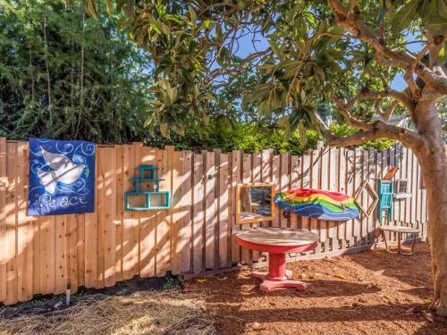 a wooden fence with a table and a chair next to a tree at Santa Cruz Style Beach retreat, 5min walk to beach in Santa Cruz
