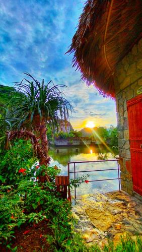 a sunset over a body of water with a hut at Hang Mua Eco Garden in Xuân Sơn