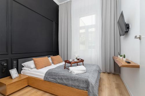 Schlafzimmer mit einem Bett mit einem schwarzen Kopfteil und einem Tisch in der Unterkunft Apartment with Mezzanine - Ariańska 14 by Renters in Krakau