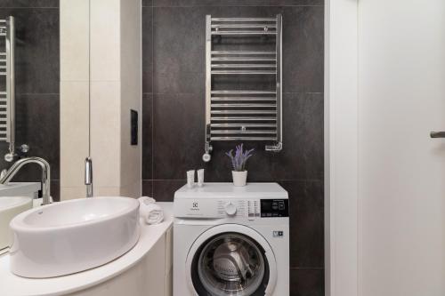ein Badezimmer mit einer Waschmaschine und einem Waschbecken in der Unterkunft Apartment with Mezzanine - Ariańska 14 by Renters in Krakau