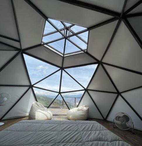 コパカバーナにあるGlamping ecoglam Medellínのベッドルーム1室(大きなガラス天井、ベッド1台付)