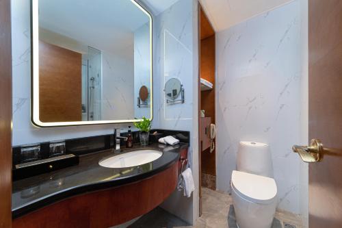 a bathroom with a sink and a toilet and a mirror at Xiamen Xiang An Yi Hao Hotel in Xiamen